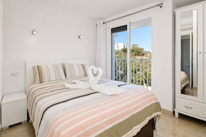 Une chambre Ă coucher avec un lit, une table de chevet, une armoire et un balcon avec vue.