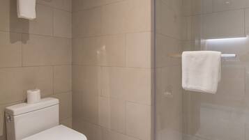 A modern bathroom with a toilet, a glass shower enclosure, and a towel rack.