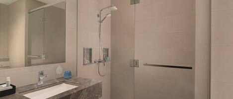 A modern bathroom with a glass-enclosed shower, a marble sink, and a large mirror.