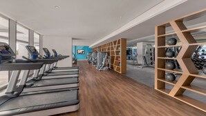 A gym with treadmills, weight machines, and a wooden wall with exercise balls. - Citadines Bay City Manila (Pasay)