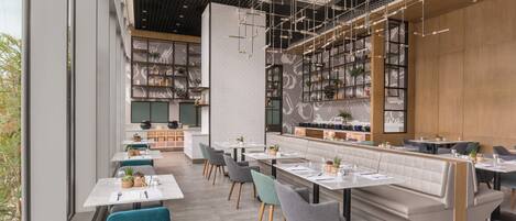 A modern restaurant interior with high ceilings, exposed ductwork, and a mix of seating arrangements including tables and booths.