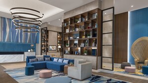 A modern living room with a sectional sofa, ottomans, a bookshelf, and a decorative wall. - Citadines Bay City Manila (Pasay)