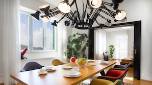 A dining area with a long wooden table, multiple chairs, and a modern chandelier.