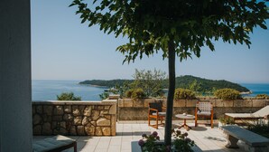A patio with stone walls, a wooden bench, a table, and a chair.
