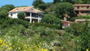 A house with a tiled roof, surrounded by lush greenery and flowering plants. - Dream holidays in Sardinia! (Chia)