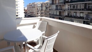 A balcony with a table and chairs, overlooking a multi-story residential building with balconies. - Mira Praia 4- Family, 2 Bedrooms and 2 Bathrooms, Wi-Fi and 80 Meters Beach (Quarteira)