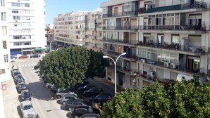 A multi-story residential building with balconies, parked cars, and a street in the foreground. - Mira Praia 4- Family, 2 Bedrooms and 2 Bathrooms, Wi-Fi and 80 Meters Beach (Quarteira)