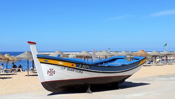 A boat with the registration number O-2017-L on a beach with thatched umbrellas and a clear sky. - Mira Praia 4- Family, 2 Bedrooms and 2 Bathrooms, Wi-Fi and 80 Meters Beach (Quarteira)