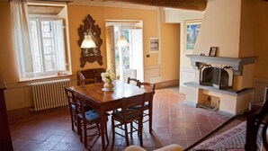 A dining area with a wooden table and chairs, a radiator, and a fireplace.