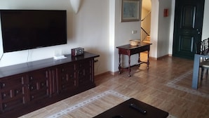 Ein Wohnzimmer mit Flachbildfernseher, Radio und einem Tisch mit Stühlen.