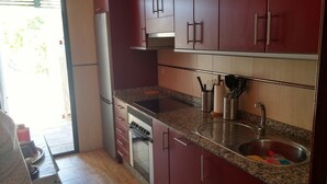 Eine kleine Küche mit Kühlschrank, Herd, Spüle und einer Arbeitsplatte aus Granit.