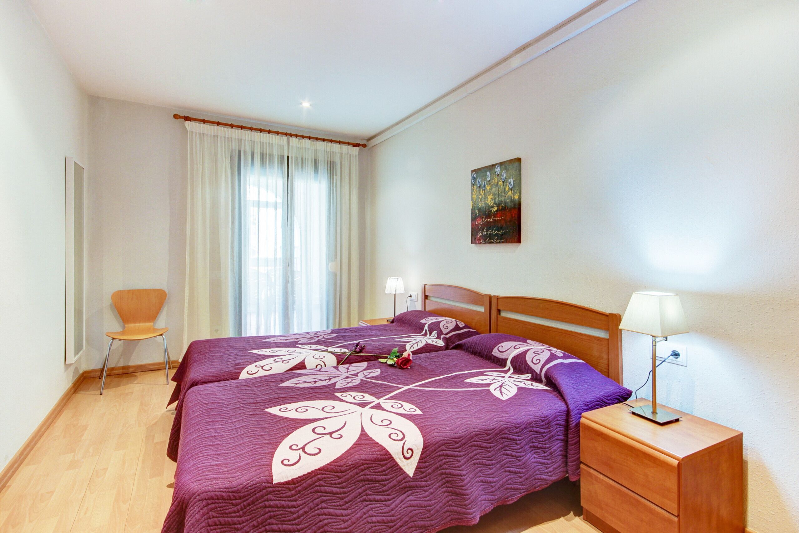 Une chambre à coucher avec un lit, une chaise, une table de chevet et un tableau au mur.