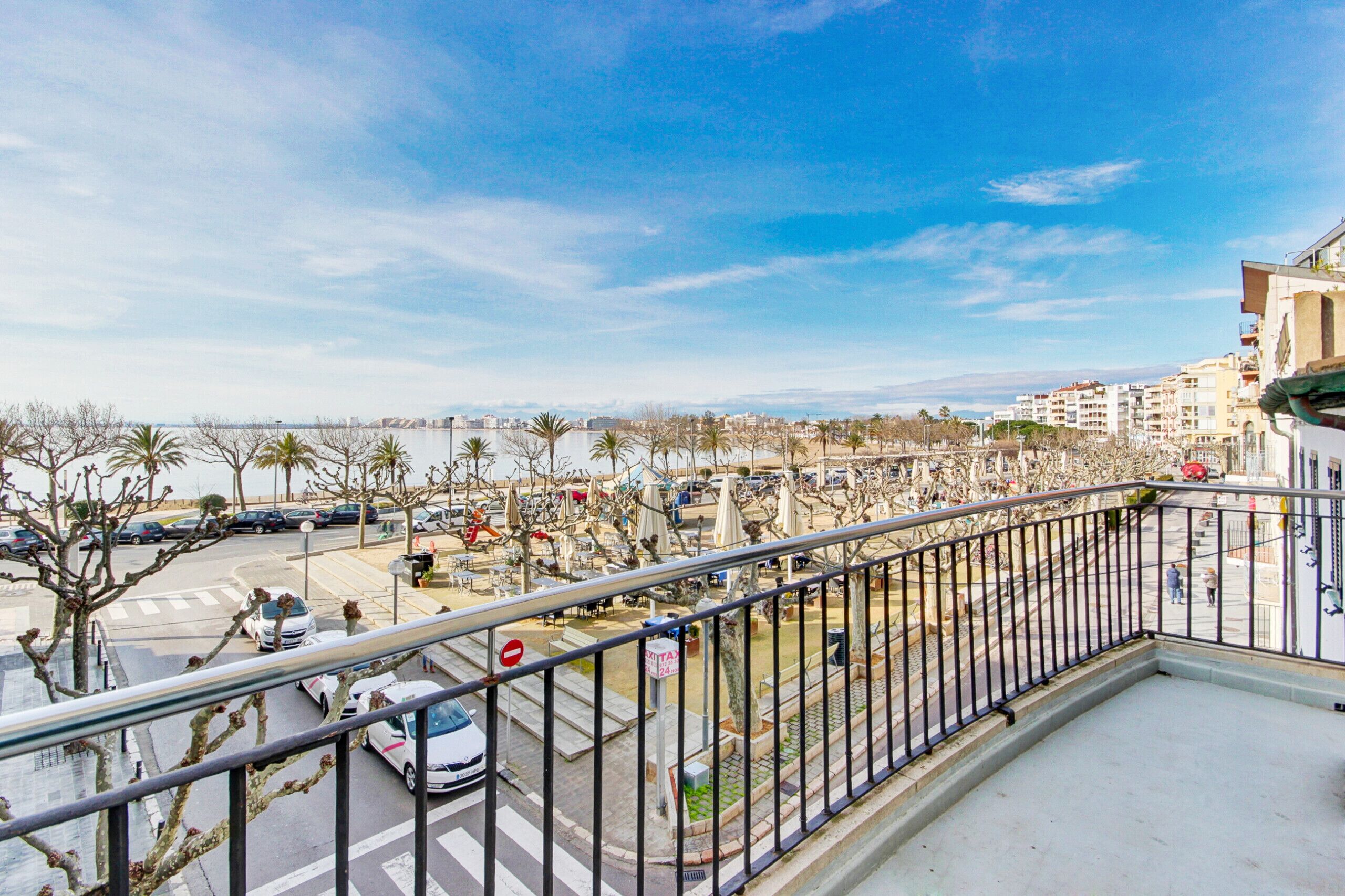 A balcony with a view of a cityscape, including buildings and a body of water.