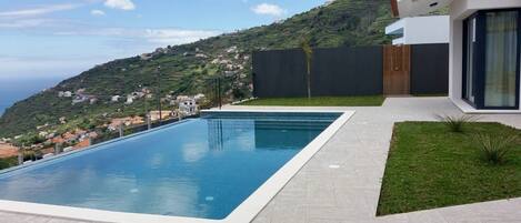 Een buitenzwembad, een verwarmd zwembad, ligstoelen bij het zwembad