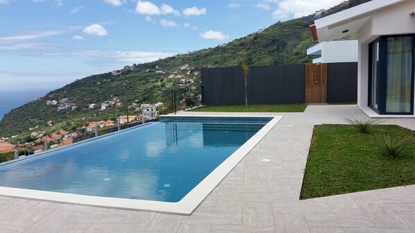 Ein moderner Pool mit freiem Blick auf eine an einem Hügel gelegene Stadt im Hintergrund.