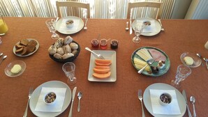 A dining table set with plates, bowls, and cutlery, surrounded by chairs. - Lomolen B&B (Aalter)