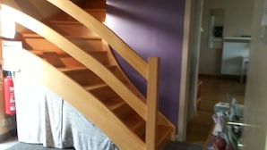 A staircase leading to an upper floor, a grey carpet, and a small table with a vase. - Lomolen B&B (Aalter)