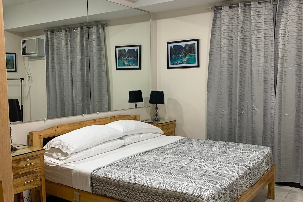 A bedroom with a wooden bed, two bedside tables, a mirror, and two framed pictures on the wall.