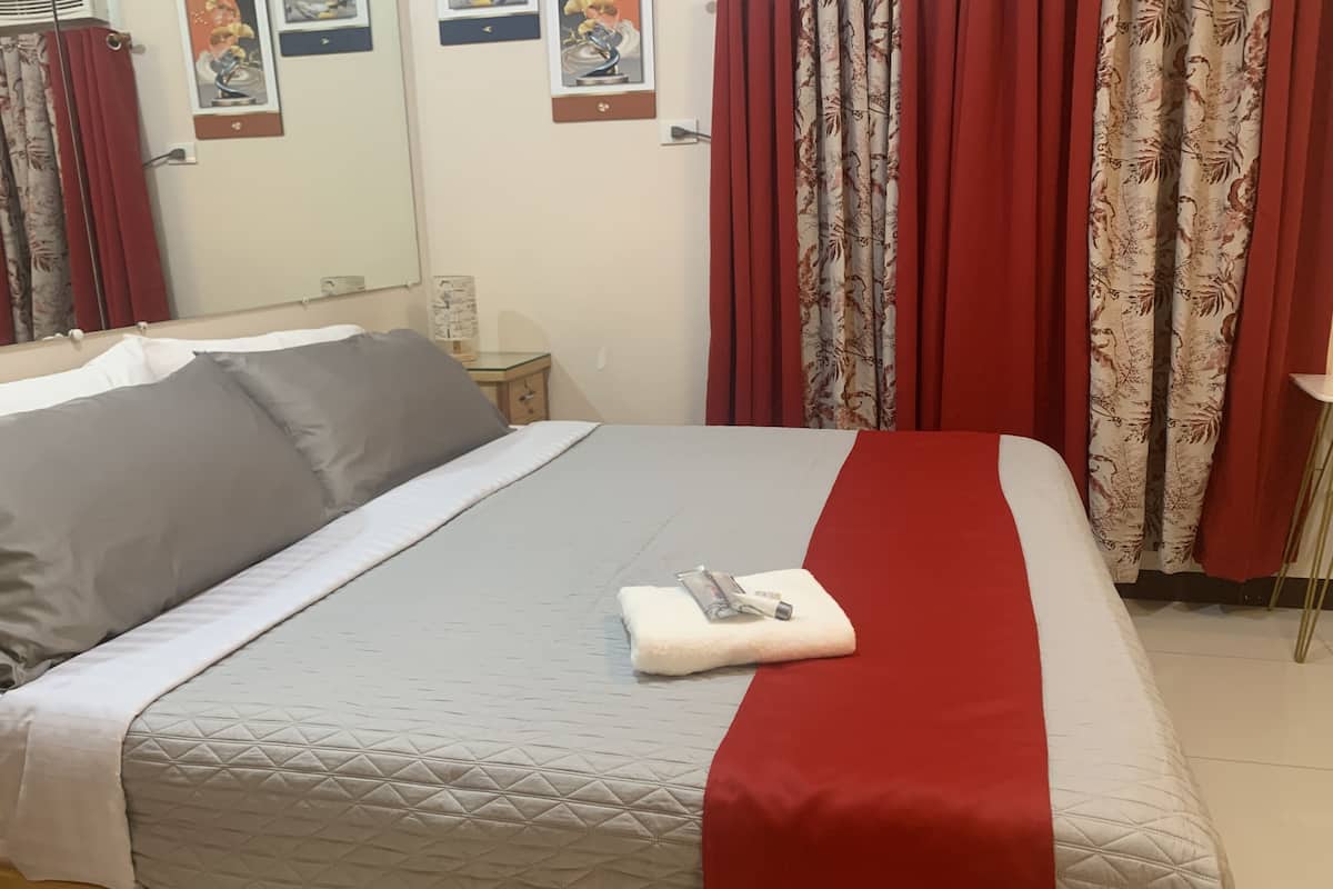 A neatly made bed with a quilted mattress, pillows, and a folded towel.