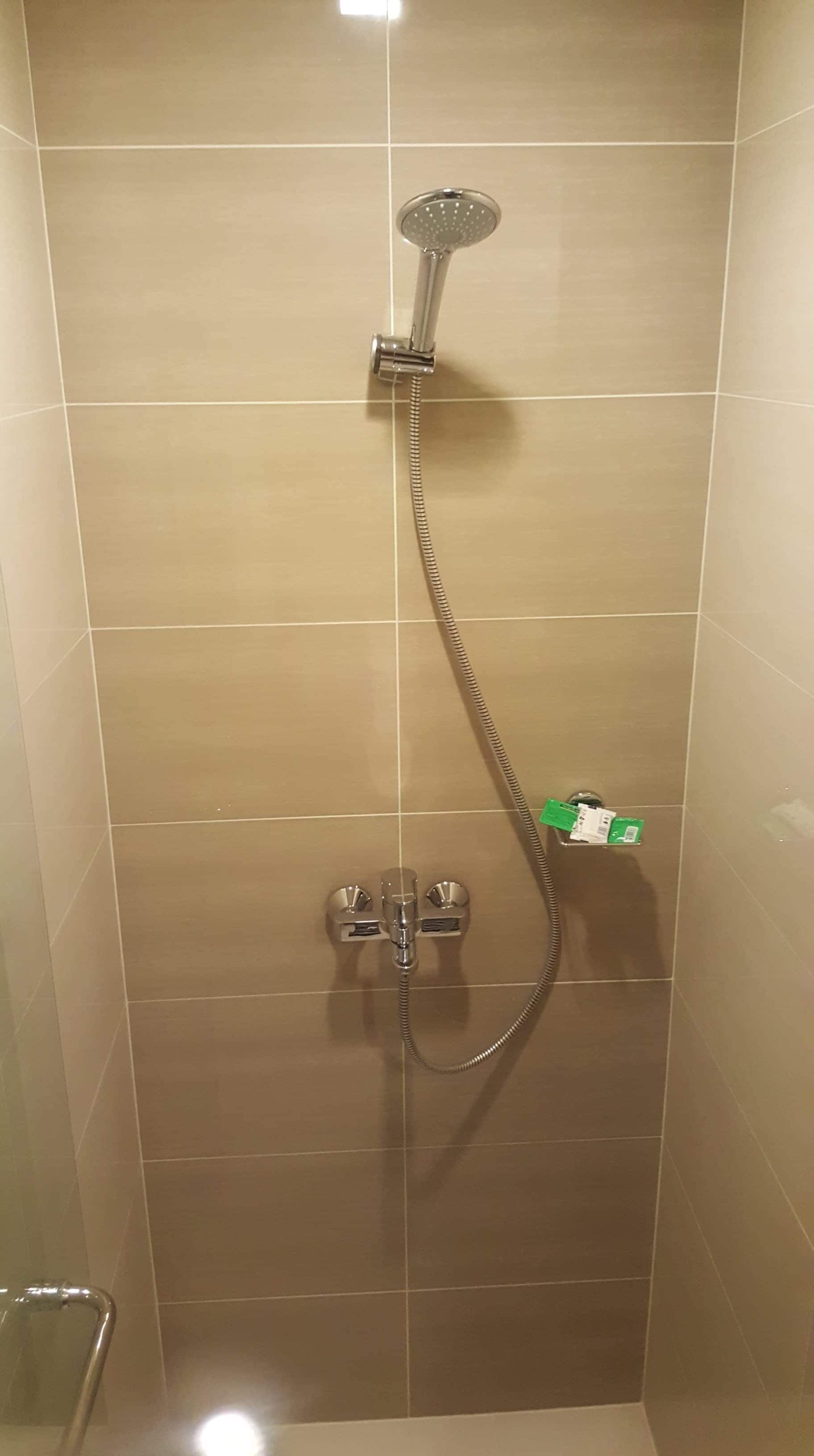 A shower with a handheld showerhead, a handheld shower attachment, and a handheld shower hose.