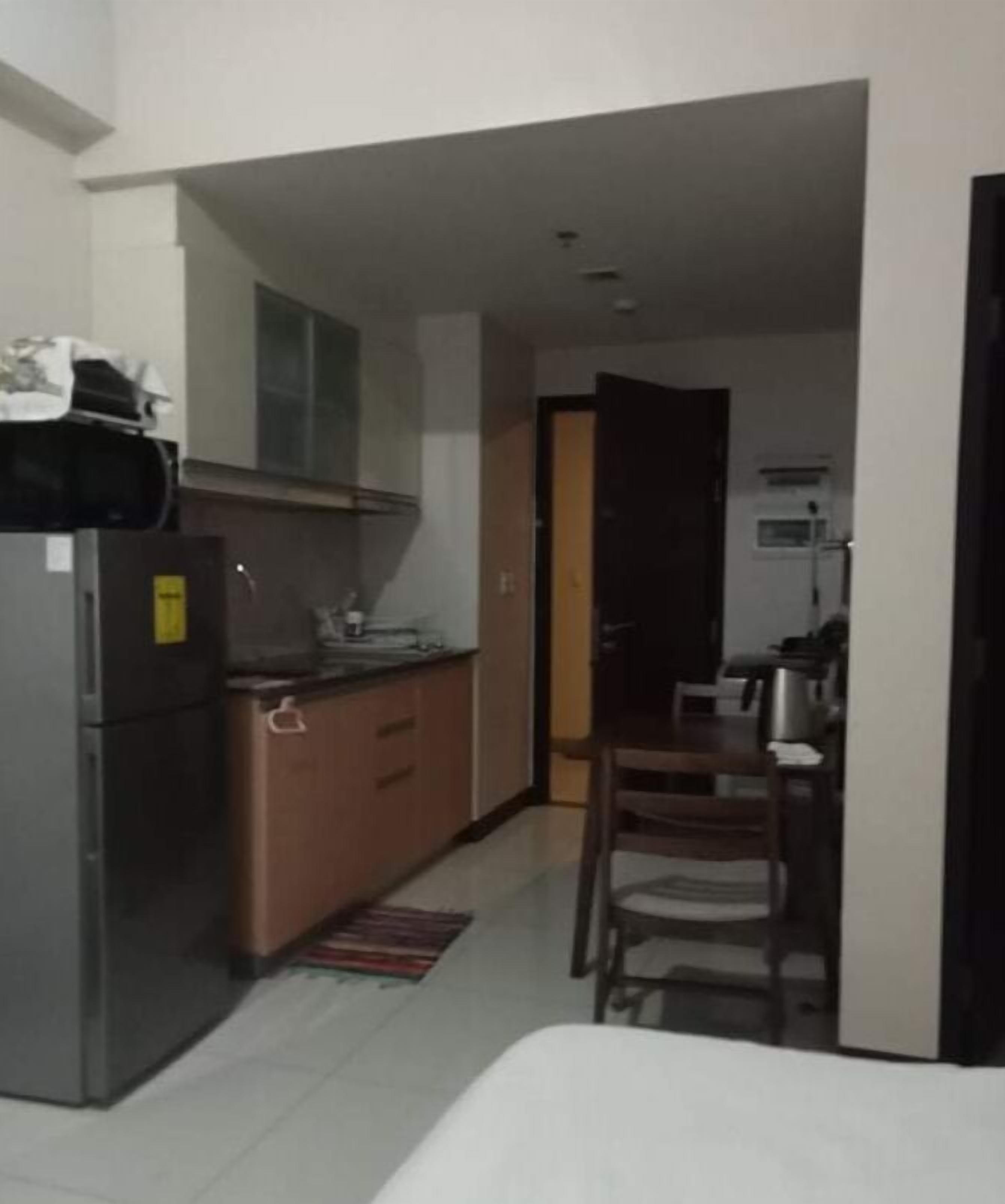 A compact kitchen with a refrigerator, a microwave, and a small dining area with a chair and table.