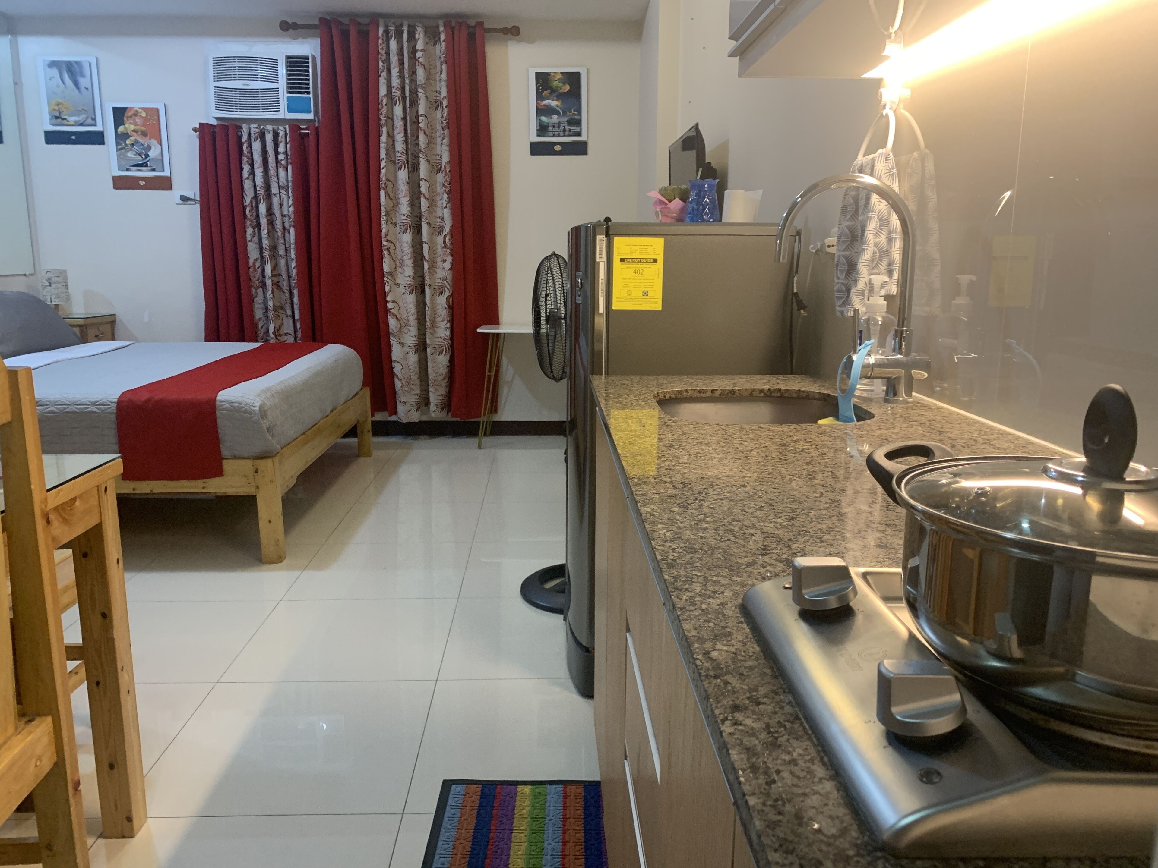 Una habitación funcional con cama, kitchenette pequeño y baño.