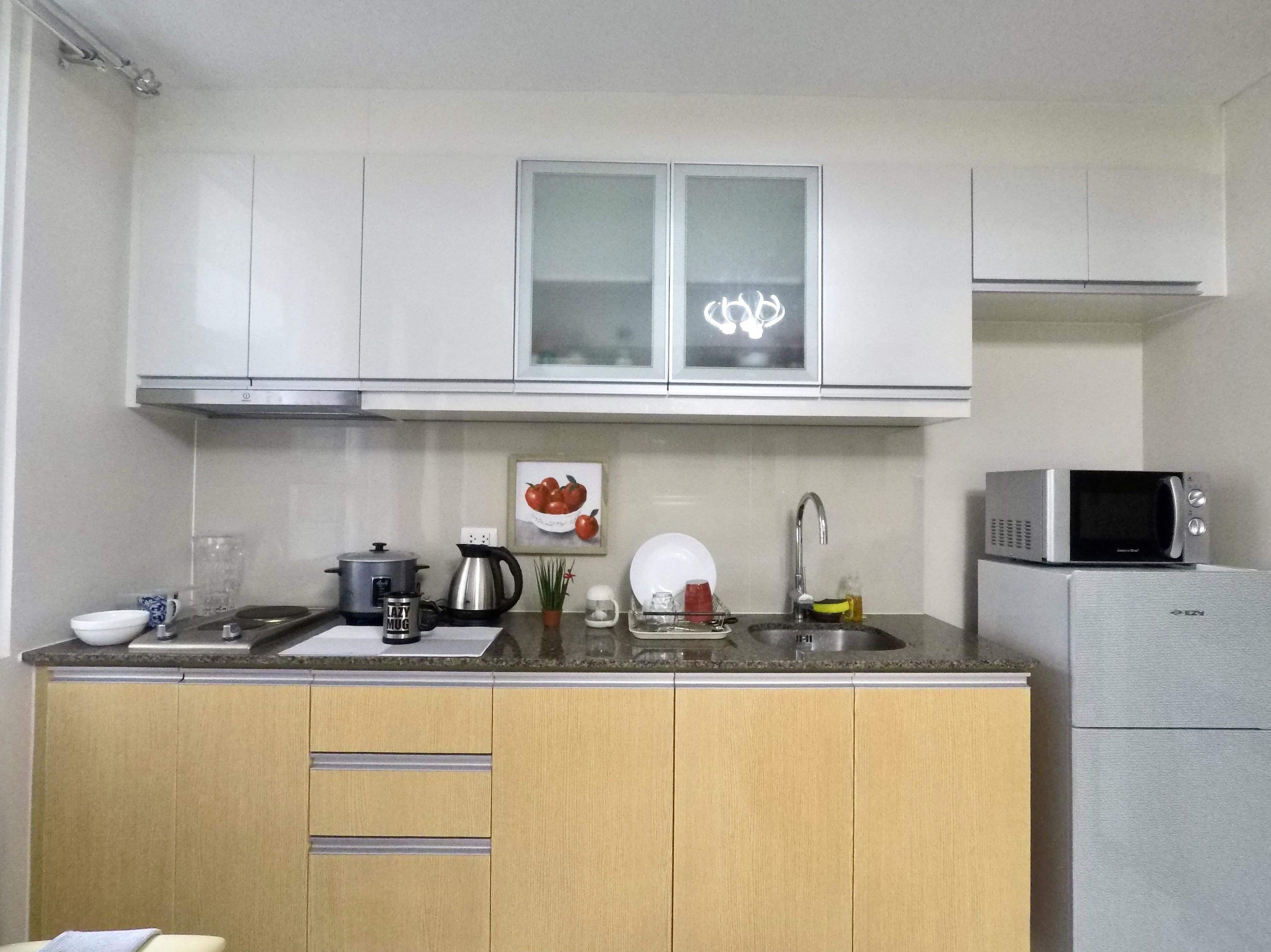 A compact kitchen with white cabinets, a microwave, a sink, and a stove.