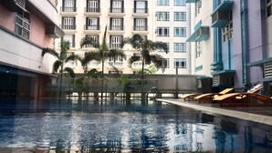 Una piscina interior con agua cristalina, rodeada de sillones de descanso y palmeras.