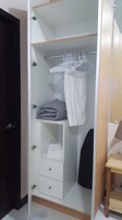 A walk-in closet with a hanging rack, shelves, and drawers.