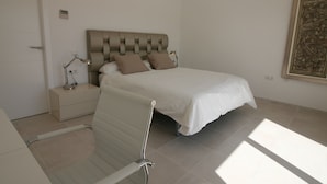 Un dormitorio con cama, mesitas de noche, un escritorio y una silla.