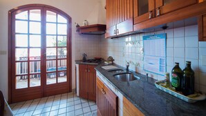 A kitchen with wooden cabinets, a sink, and a tiled backsplash. - Barabba sea house (Santa Teresa di Riva)