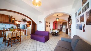A spacious living area with a purple sofa, a grey couch, and a dining table with chairs. - Barabba sea house (Santa Teresa di Riva)