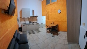 Ein kompakter Wohnraum mit Küchenzeile, Essbereich und Sitzgelegenheit.