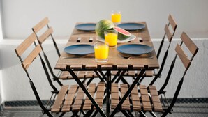 Una mesa de madera con cuatro sillas, dos platos, dos vasos y una sandía.