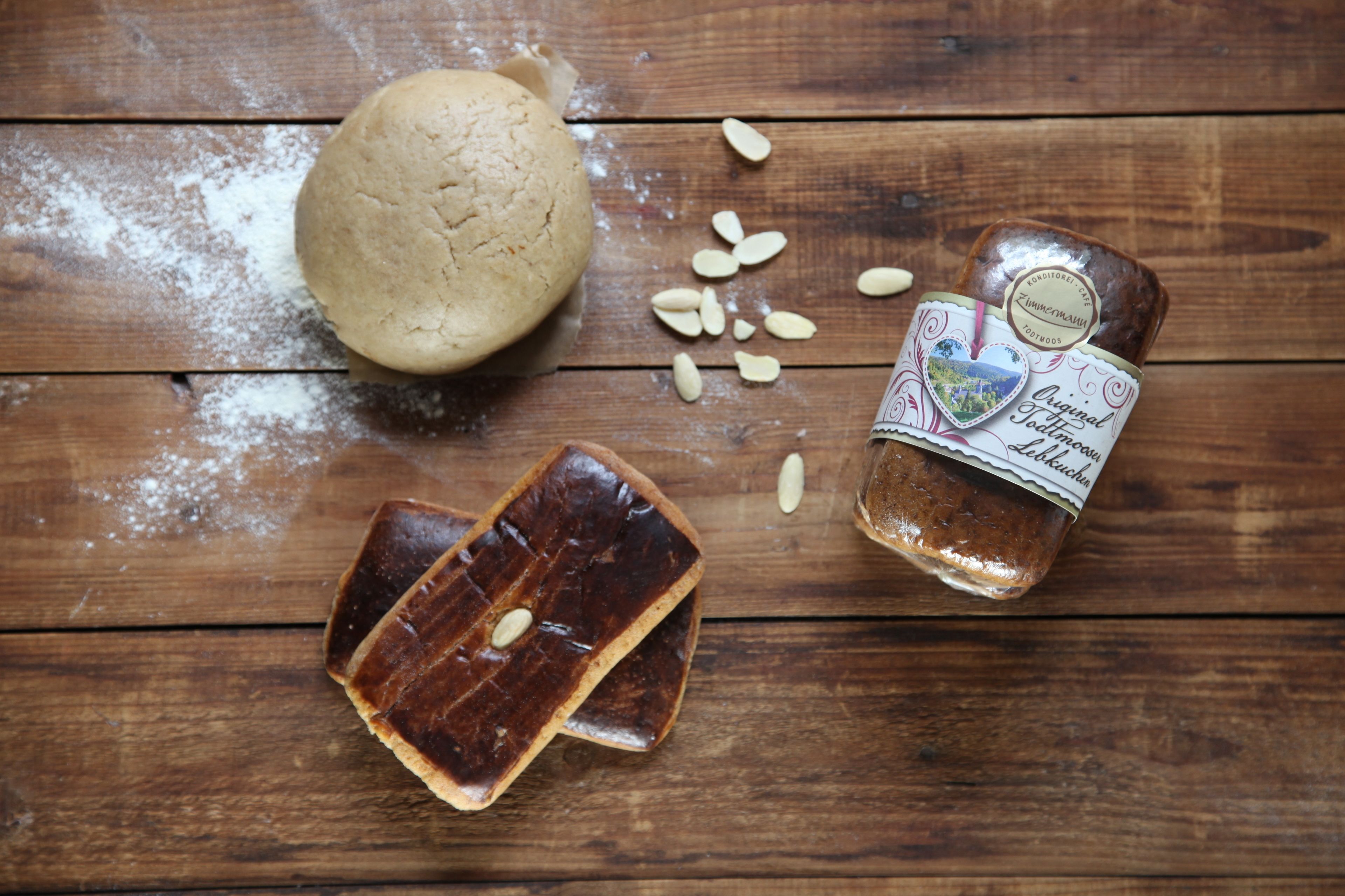 Une miche de pain, un pot de pâte à tartiner et des tranches de pain sur une surface en bois.
