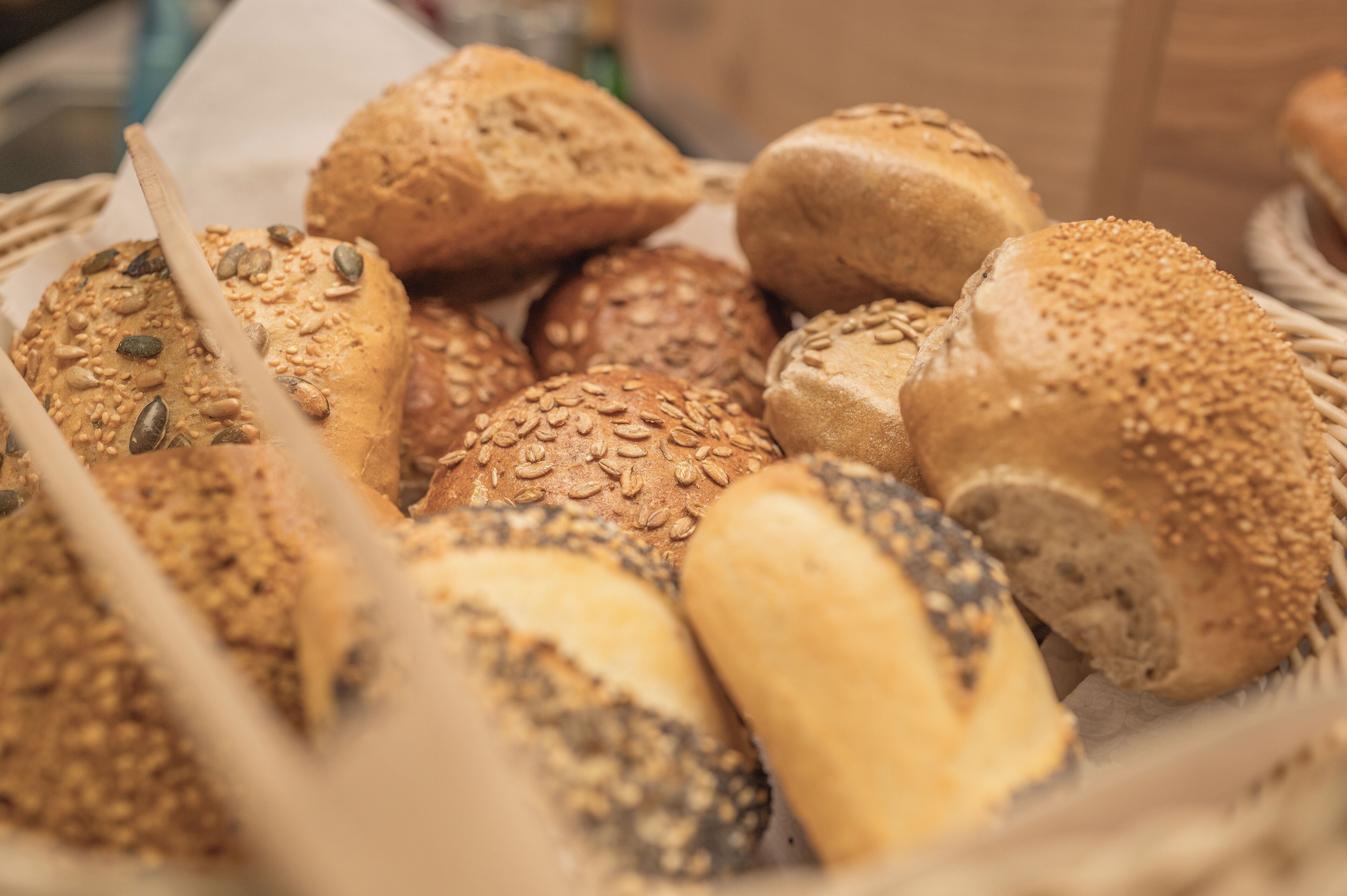 A basket of various breads with seeds and sesame seeds.