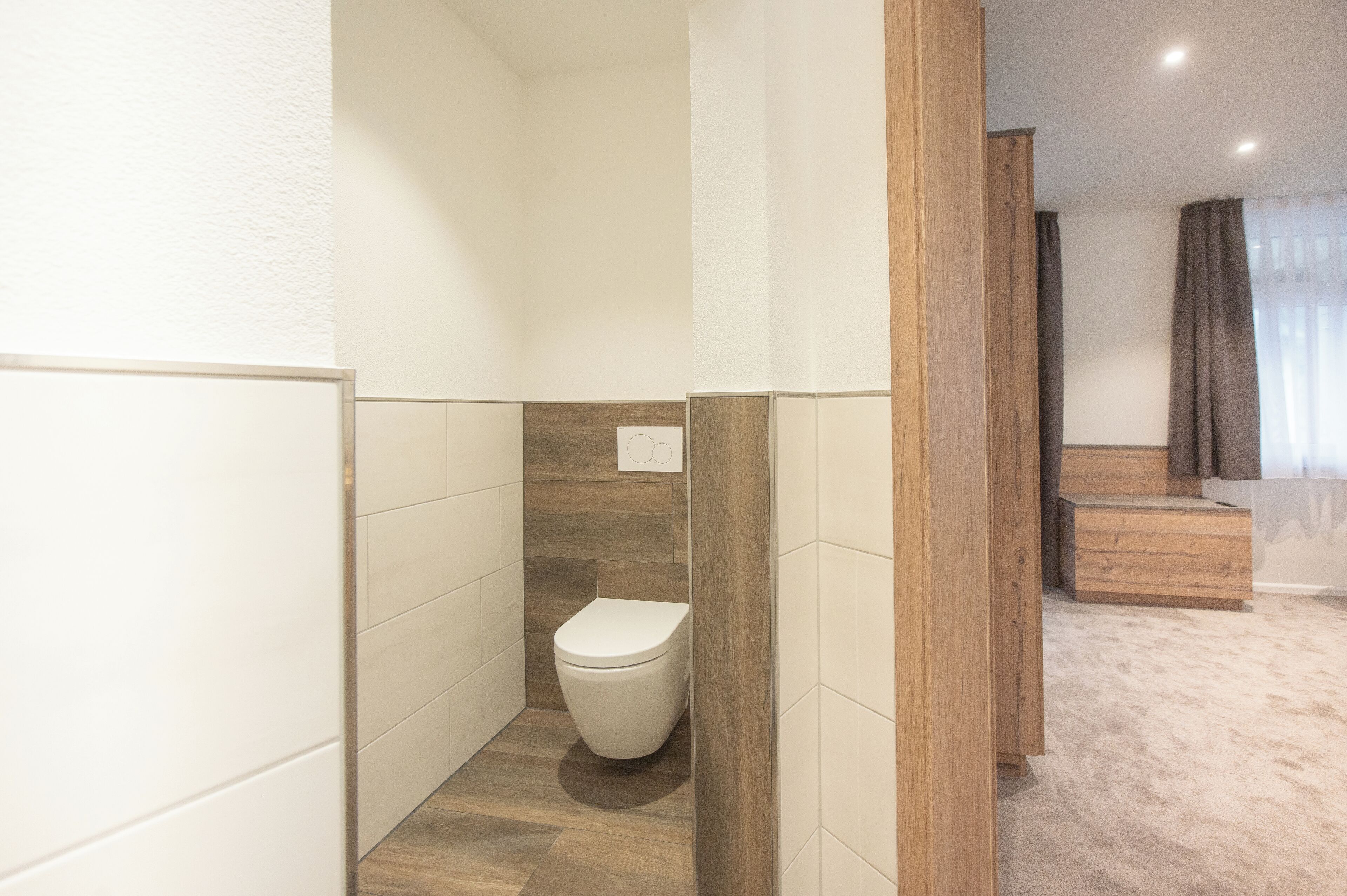 Een moderne badkamer met toilet, houten accenten en een vloerbedekking.