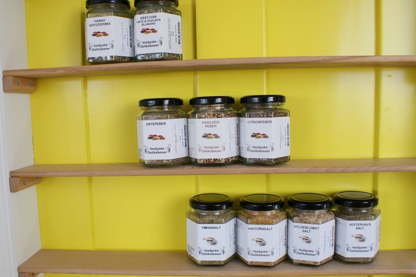 A shelf with various food items, including spices and salts.