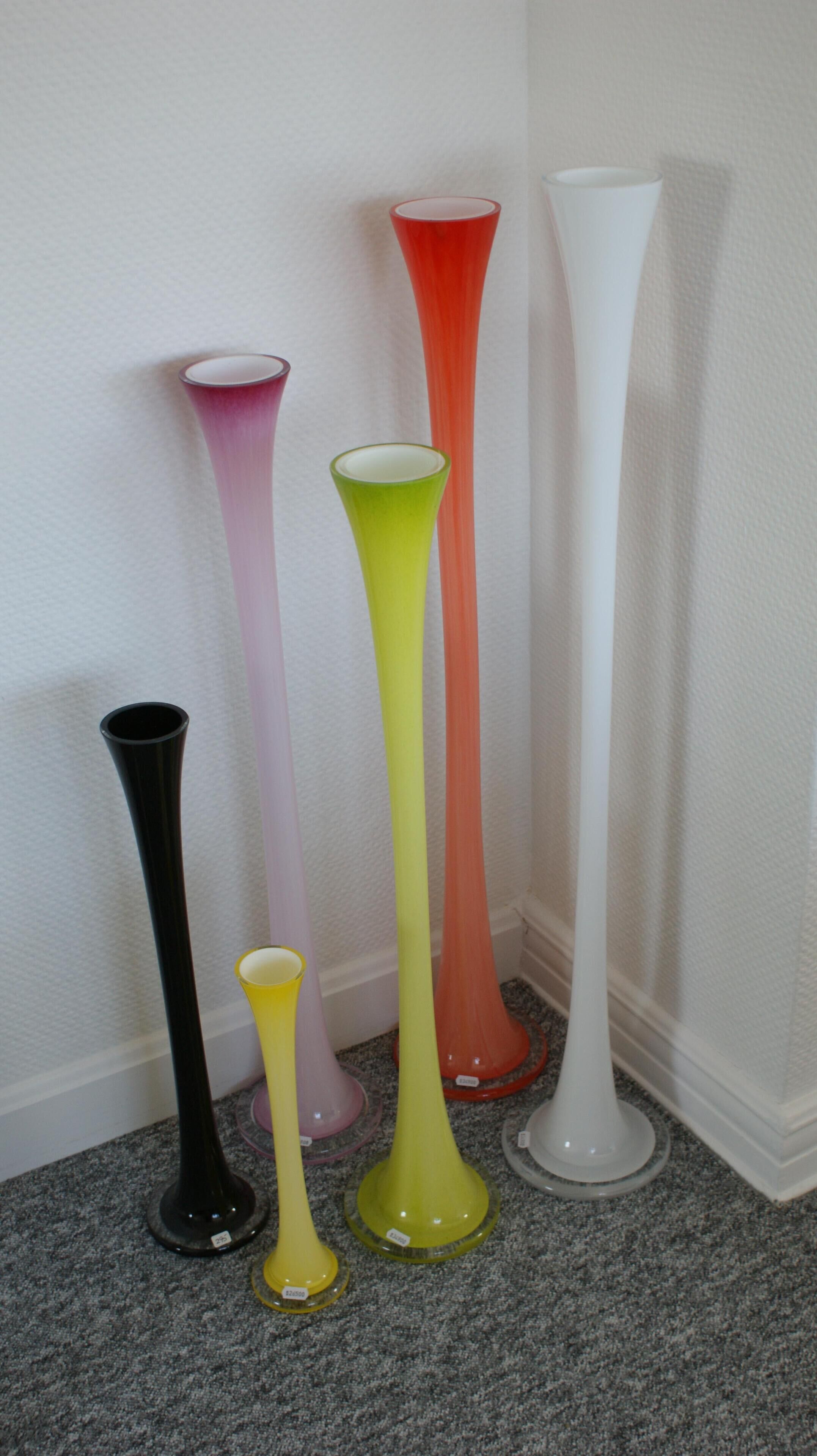 A collection of colorful vases arranged against a wall.