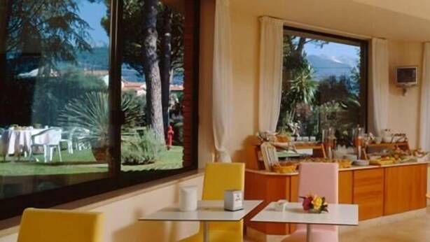 A hotel room with a large window offering a view of the outdoors, a dining area with a buffet, and a seating area with tables and chairs. - Hotel Da Filiè (Seravezza)