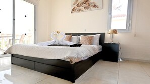 Quarto de hotel com cama, mesa de cabeceira, luminária e quadro na parede.