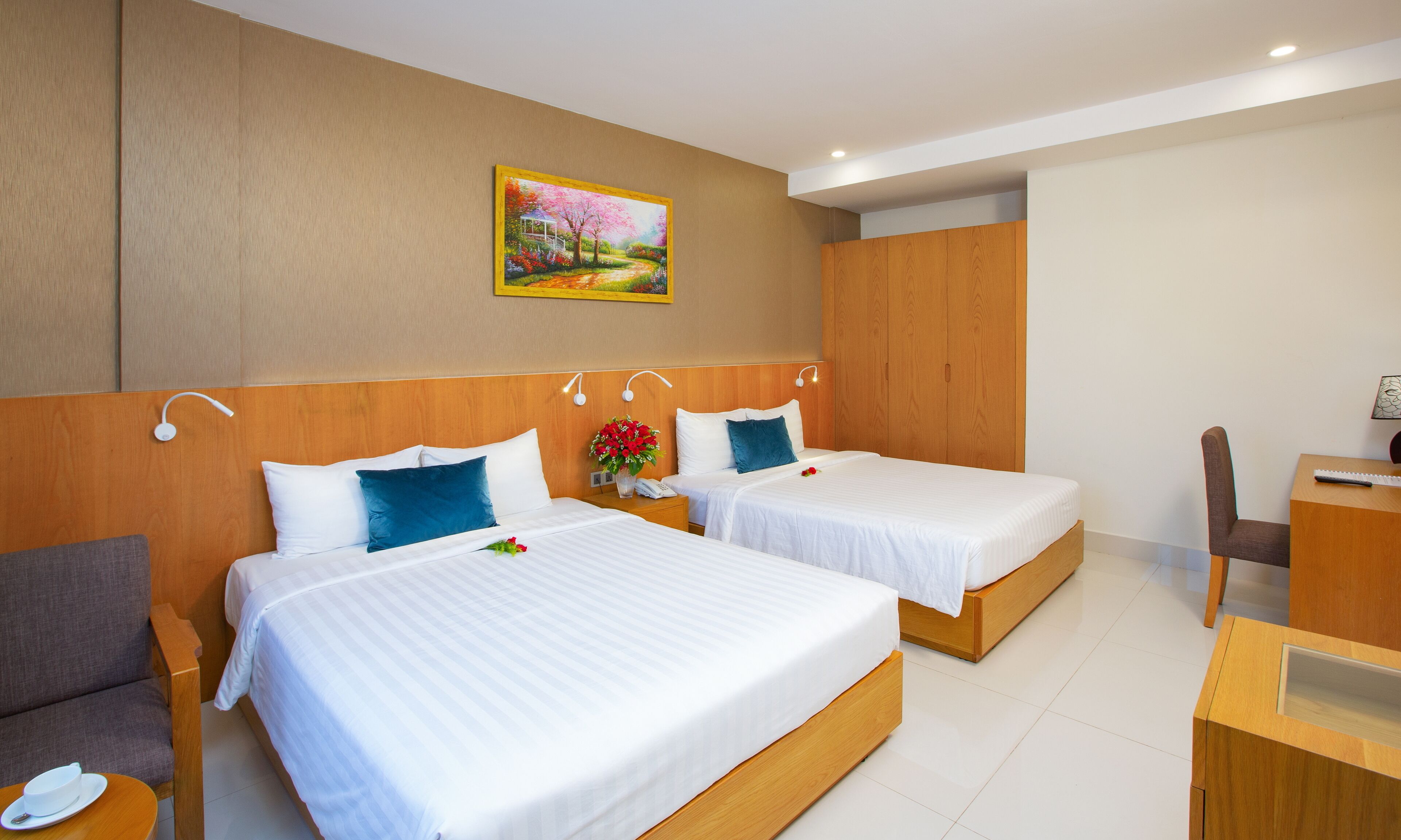 Ein Hotelzimmer mit zwei Betten, Holz-Kopfteilen, einem Schreibtisch und einem Stuhl.