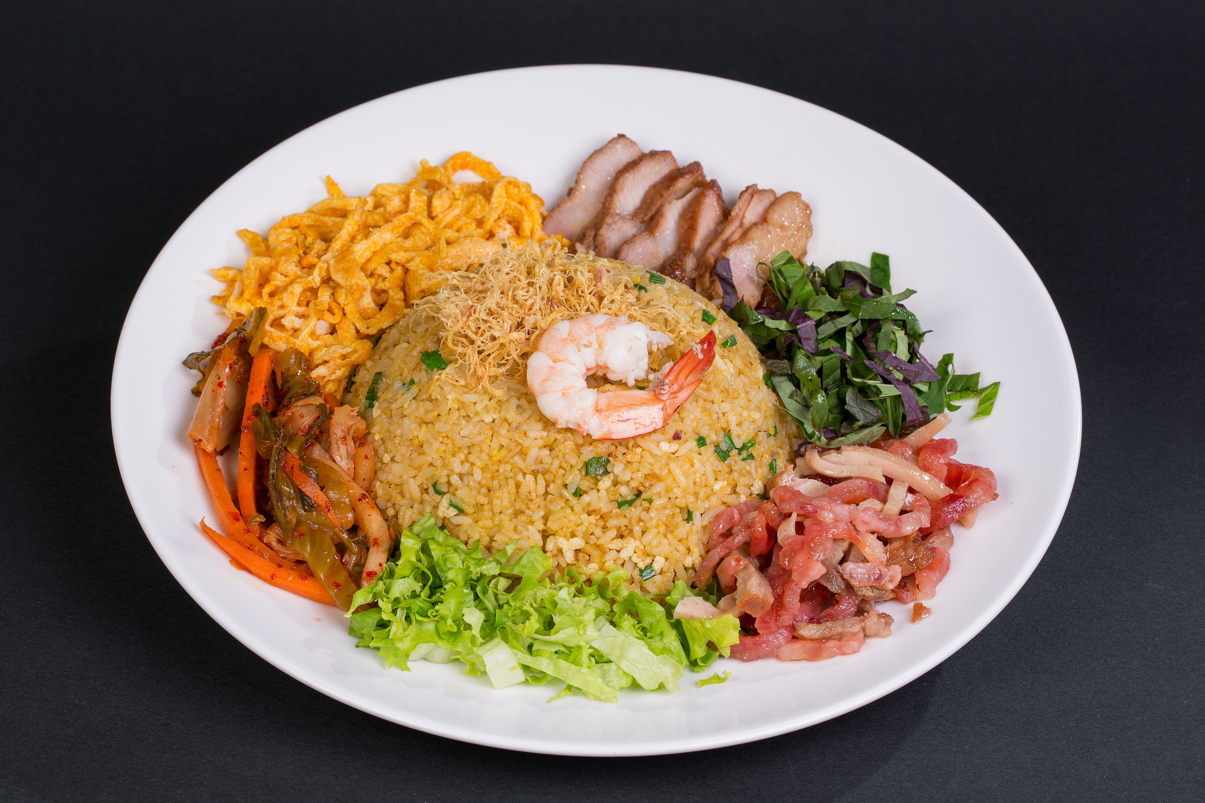 Une assiette de nourriture contenant du riz, des crevettes, des légumes et de la viande.