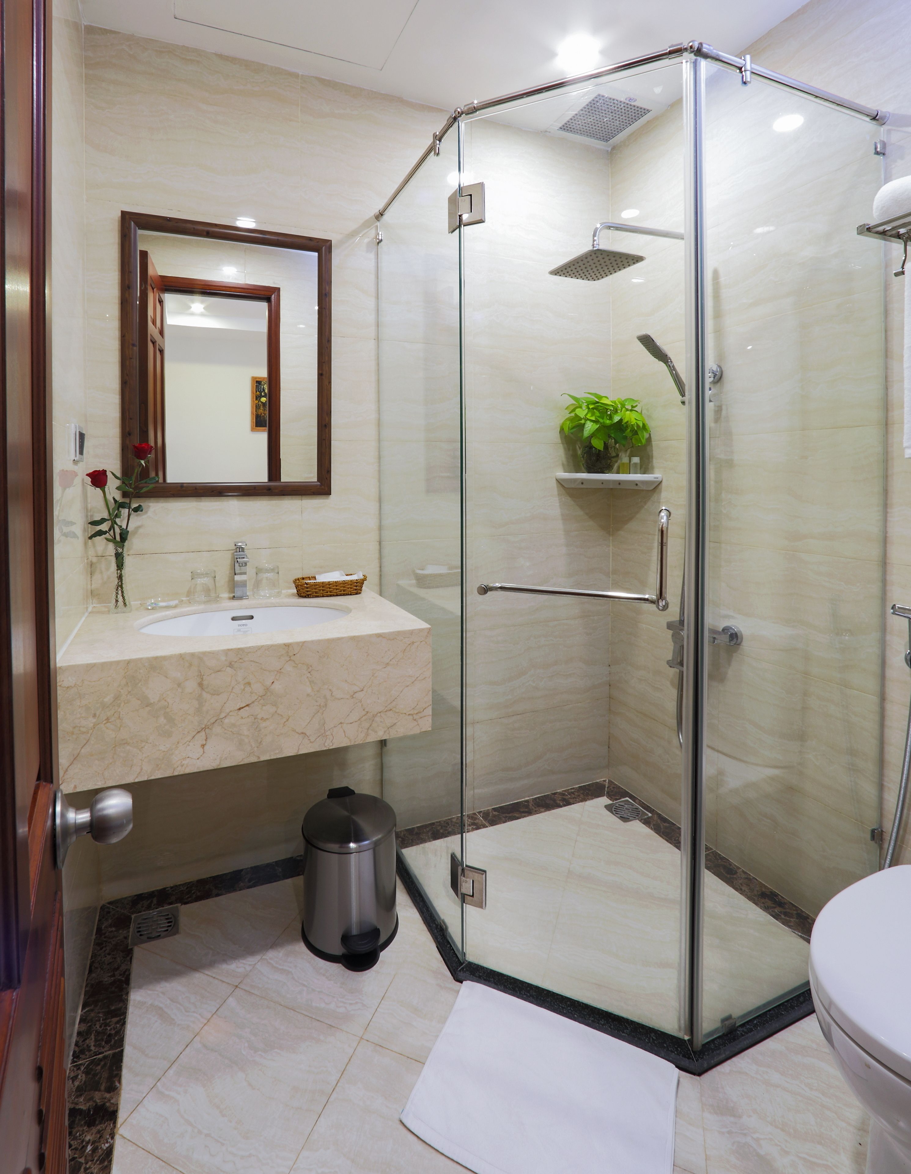 A modern bathroom with a glass-enclosed shower, a marble sink, and a mirror above the vanity.