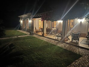 A house with a covered patio, outdoor furniture, and a well-maintained lawn.