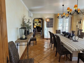 A dining area with wicker chairs, a long table, and a chandelier. - Villa Malveira - Style and Tradition in Portugal (Janes)