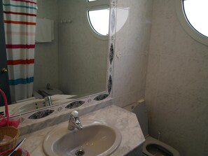 Un baño con lavamanos, espejo e inodoro.
