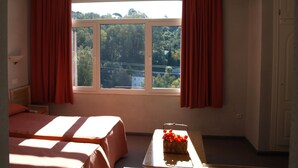 Une chambre d’hôtel avec deux lits, une petite table sur laquelle est posé un vase de fleurs et une fenêtre avec des rideaux.