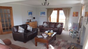 A living room with two brown leather sofas, a wooden coffee table with magazines, and a television on a stand. - A Beautiful Rural Farmhouse With Flexible Living Space And Great Views (Stirling)