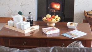 A wooden table with a tea set, a coffee maker, a bowl of fruit, and a magazine. - A Beautiful Rural Farmhouse With Flexible Living Space And Great Views (Stirling)